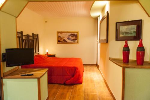 - une chambre avec un lit rouge et une télévision dans l'établissement La Dimora Antica, à Viggianello