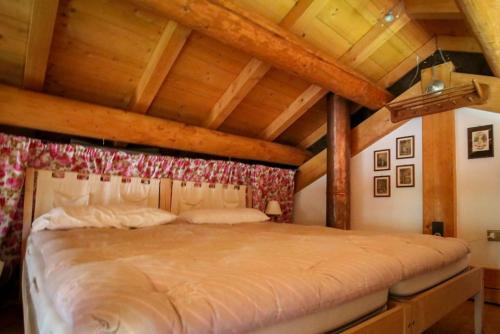 a large bed in a room with wooden ceilings at Baita Agaz in Sovramonte