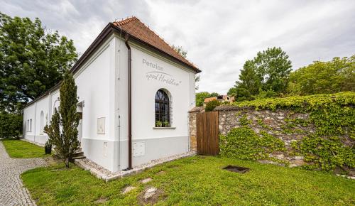 a small white building next to a stone wall at Penzion Pod hrádkem in Mikulov