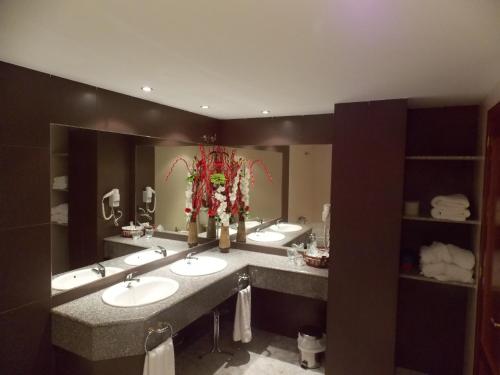 a bathroom with three sinks and a large mirror at Hotel San Cristobal in Coria
