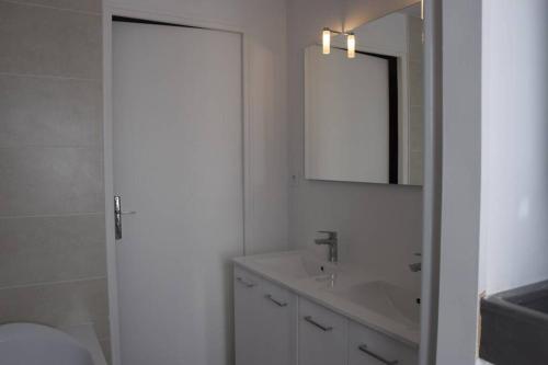 La salle de bains blanche est pourvue d'un lavabo et d'un miroir. dans l'établissement A 20 mn du Puy du Fou coquette et fonctionellle, à Mauléon