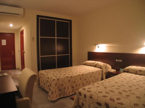 a hotel room with two beds and a window at Hotel San Cristobal in Coria
