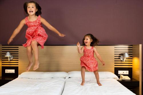 two little girls jumping on a bed at Oroel Hotel & SPA in Jaca