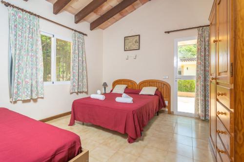 um quarto com 2 camas e lençóis vermelhos em Can Capulla 6 em Ses Covetes