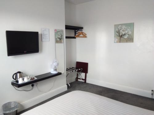 um quarto com uma cama e uma televisão na parede em Comfort Guest House em Leicester