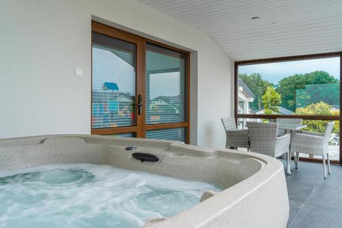 a jacuzzi tub in a room with a patio at Duet Domki in Jarosławiec