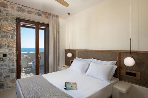 a bedroom with a bed with a view of the ocean at The Authentic Village Boutique Hotel in Khóra Sfakíon