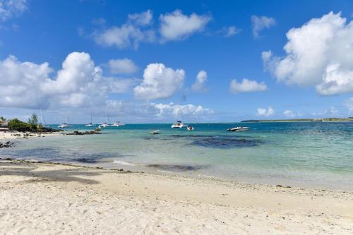 a sandy beach with boats in the water at Turquoise Bay Beach Apartments Trou d'Eau Douce in Trou dʼ Eau Douce