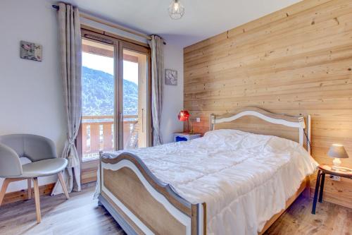 een slaapkamer met een bed en een groot raam bij ALTAKA 3 in Morzine