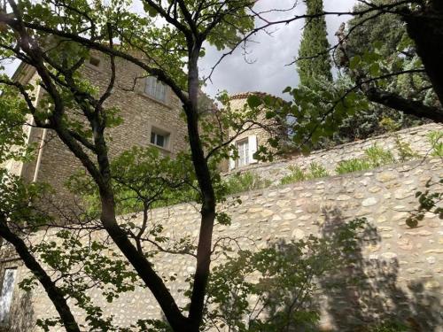 a stone wall with trees in front of a building at La Viste - SPA-JACUZZI - MASSAGE- SAUNA - 4 SAISONS - Piscine Chauffée Toute l'année - Heated POOL - 800m City Centre in Nyons
