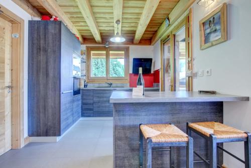 - une cuisine avec un bar avec deux tabourets dans l'établissement ALTAKA 3, à Morzine