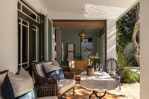 a porch with wicker chairs and a table with a table at Akademie Street Boutique Hotel in Franschhoek