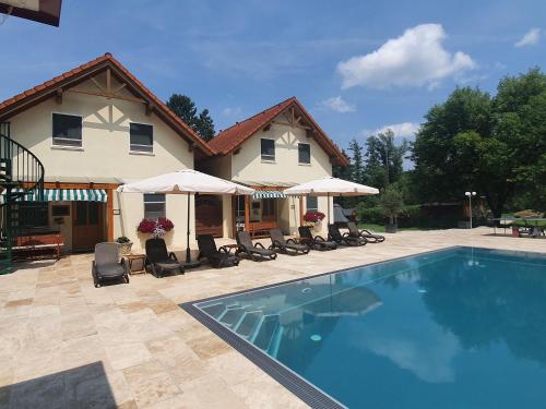 a pool in front of a house with chairs and umbrellas at Ferienanlage Beatrix in Stegersbach