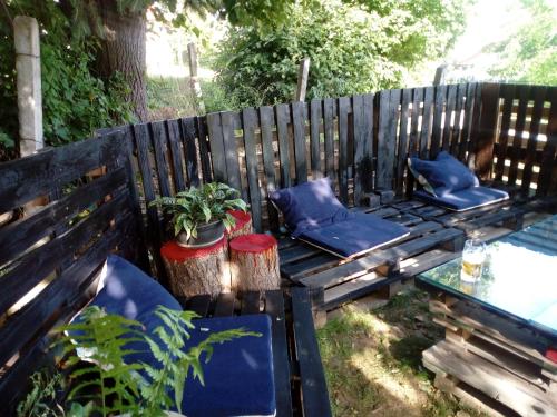 a wooden bench with blue pillows and a table at Káli Apartman in Bakonybél