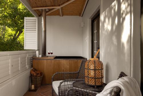 a porch with a chair and a table and a window at Akademie Street Boutique Hotel in Franschhoek