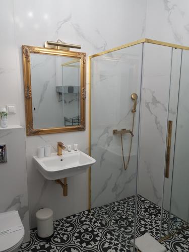 La salle de bains est pourvue d'un lavabo et d'une douche. dans l'établissement H&T Apartament Przy Starym Ratuszu, à Gdańsk