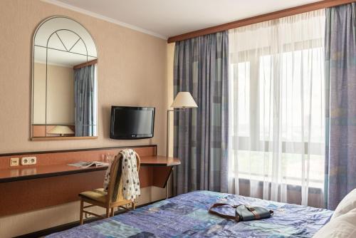 a hotel room with a bed and a desk and a television at Cosmos Hotel in Moscow