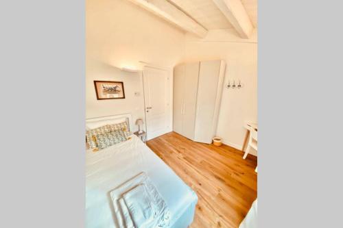 a bedroom with a white bed and wooden floors at Casa Vicolo Castello in Ravenna