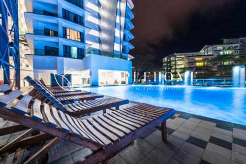 a swimming pool with lounge chairs next to a building at Geo38 Premier Suites Genting Highlands in Genting Highlands