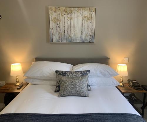 een slaapkamer met een bed met witte lakens en kussens bij The Cedar Country Hotel in Bellway