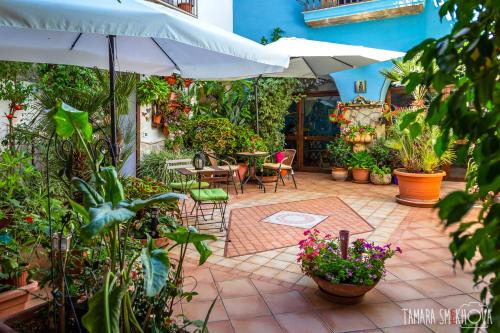 een patio met tafels, stoelen en planten bij La Finestra sul Cortile B&B in Sciacca