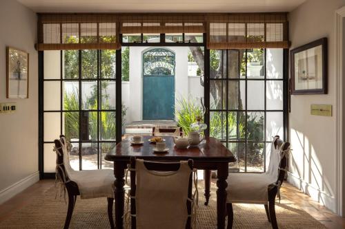 a dining room with a table and chairs and windows at Akademie Street Boutique Hotel in Franschhoek