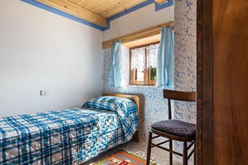 1 dormitorio con 1 cama, 1 silla y 1 ventana en Baita Località Cap, en Roncone