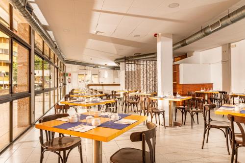 an empty restaurant with wooden tables and chairs at The BB Hotel Boutique Can Colom in Lloret de Mar