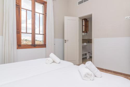two white beds in a room with a window at Can Bombarda in Llubí
