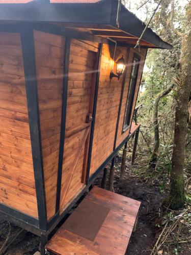 a wooden outhouse in the woods with a black roof at Mirador Bosque Gran Torino Neusa in Cogua