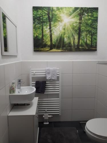 een badkamer met een wastafel en een foto van bomen bij Bauerngarten in Hofgeismar