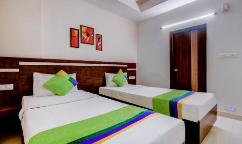 a bedroom with two beds with green and colorful pillows at Treebo Primeland Suites in Bengaluru