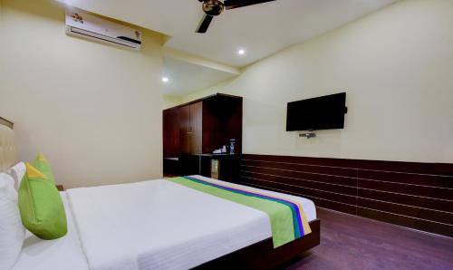 a bedroom with a bed and a flat screen tv at Treebo Primeland Suites in Bengaluru