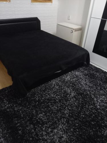un letto con una coperta nera sopra un tappeto di Bujdy Apartman a Szerencs