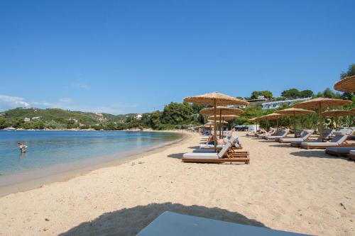 a beach with lounge chairs and umbrellas and the ocean at Amouage Boutique Home in Skiathos Town