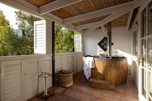 a soaking tub on a porch with a window at Akademie Street Boutique Hotel in Franschhoek