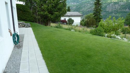 a house with a green lawn with a house at Holzji in Glis