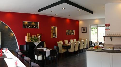 ein Restaurant mit roten Wänden, Tischen und Stühlen in der Unterkunft Hotel Dolce Vita in Bernkastel-Kues