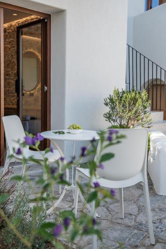 a table and chairs on a patio with purple flowers at The Authentic Village Boutique Hotel in Khóra Sfakíon