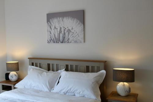 een slaapkamer met een bed met witte kussens en 2 lampen bij Beachfront Panoramic Seaview Free Wifi & Parking in Lossiemouth