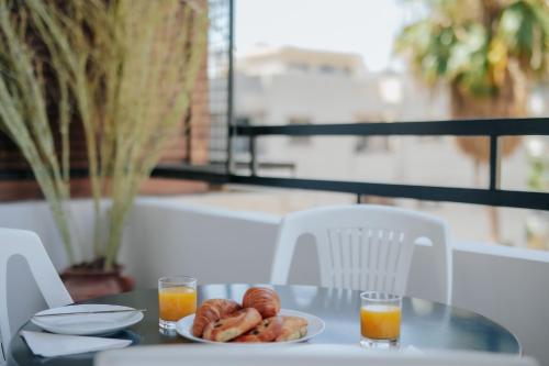 a table with a plate of donuts and two glasses of orange juice at Lazaros Centre Apartment in Larnaka