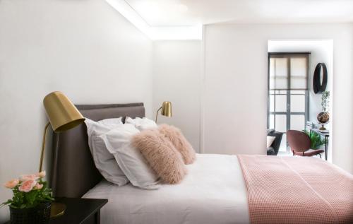 a white bedroom with a bed with white pillows at Appartements - Le Logis Versaillais in Versailles