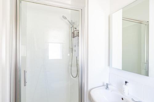 uma casa de banho com um chuveiro, um lavatório e um espelho. em Fern Lodge 2 with Hot Tub em Belladrum