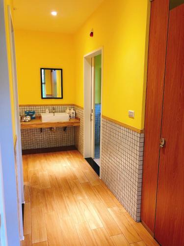 a yellow bathroom with a sink and a mirror at American Village Resort in Taipei