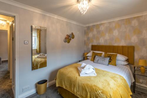 a bedroom with a bed with yellow sheets and a mirror at Number Four in Westoe
