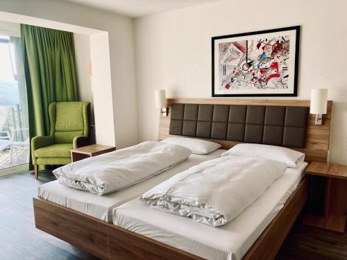a bedroom with two beds and a green chair at Berg-Gasthof Hötzelein in Kunreuth