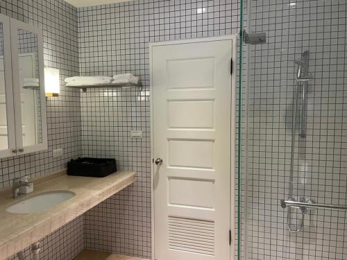 a bathroom with a sink and a glass shower door at American Village Resort in Taipei