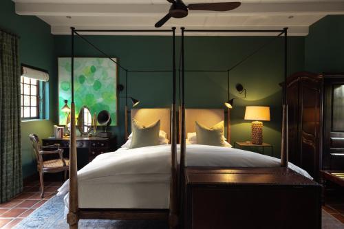 a bedroom with a canopy bed and green walls at Akademie Street Boutique Hotel in Franschhoek