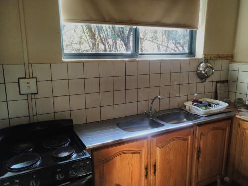 a kitchen with a sink and a stove and a window at ThabaNkwe Bushveld Inn in Thabazimbi