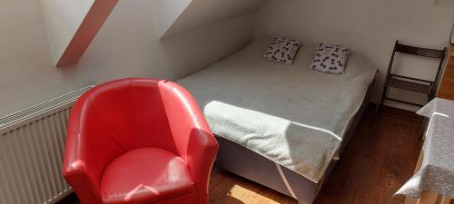 a small bed with a red chair in a room at Apartament Studio in Giżycko
